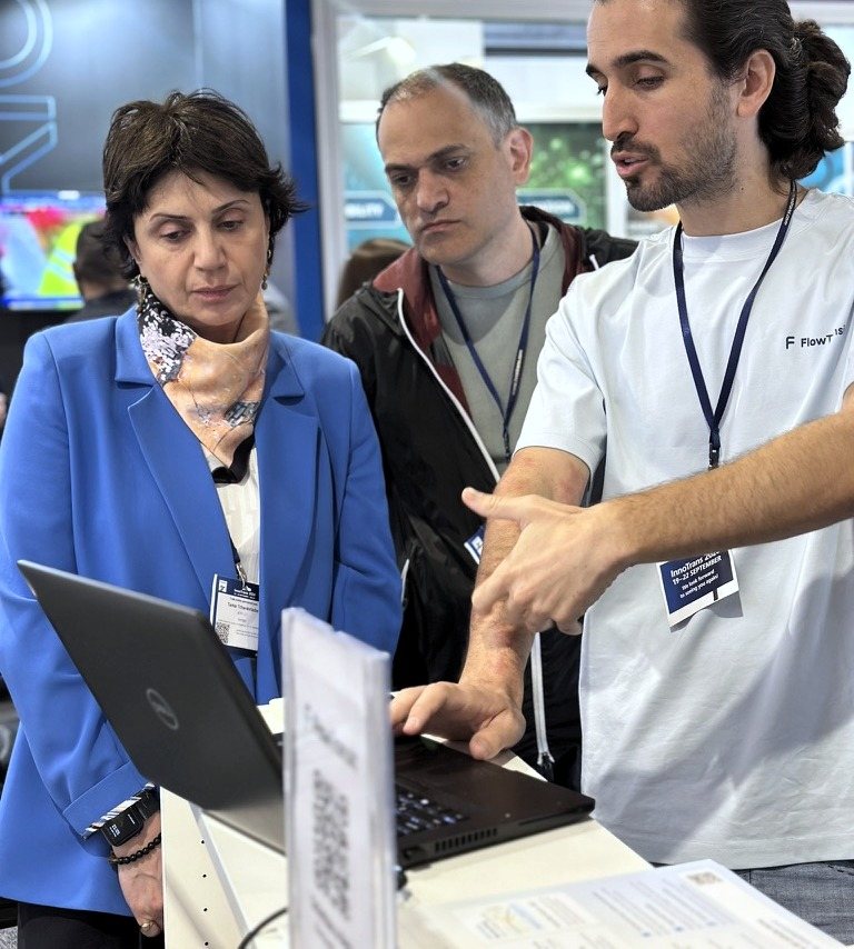 Ein Mitglied des FlowTransit-Teams führt zwei Besuchern die Planungssoftware auf einem Laptop vor