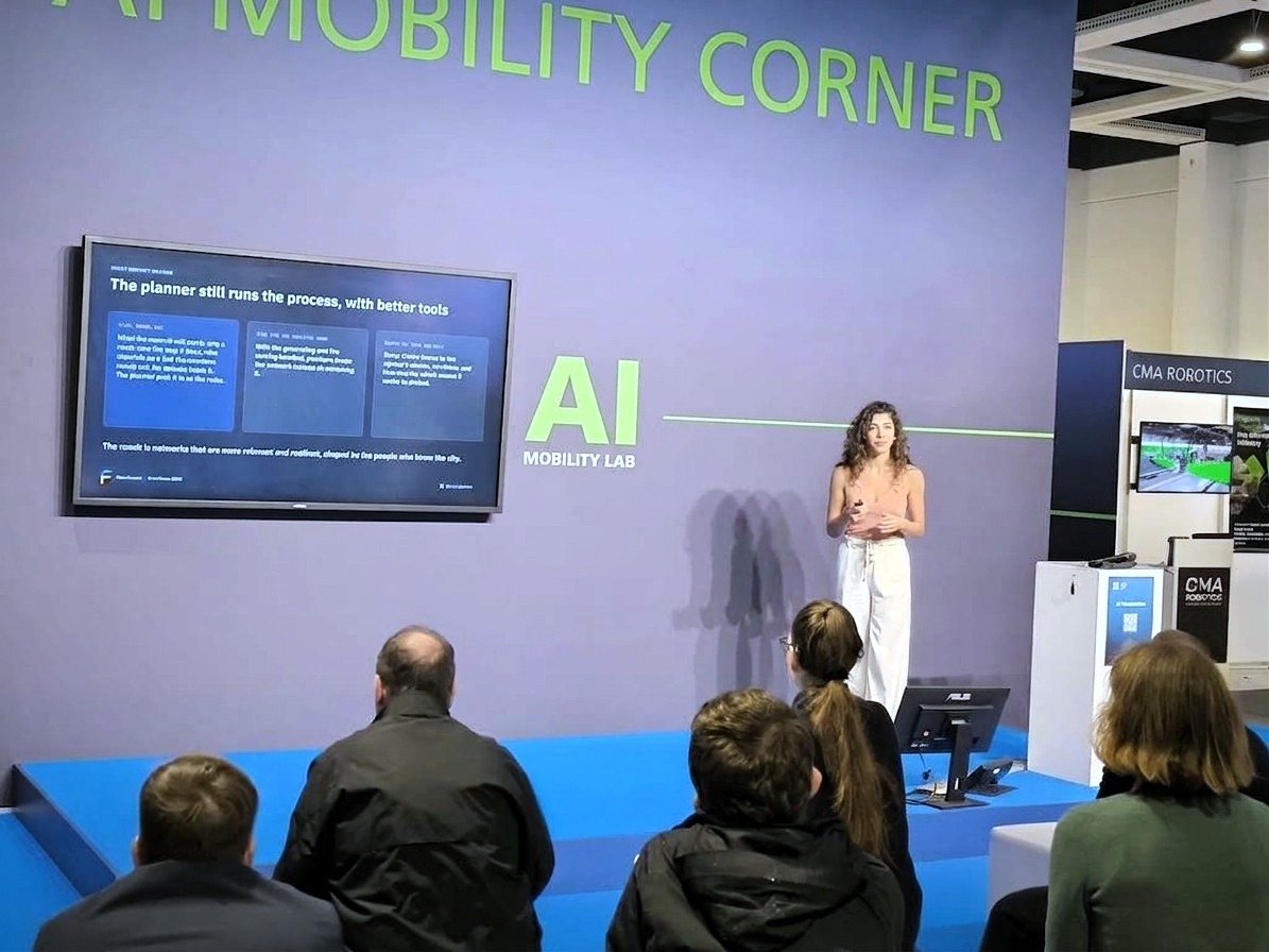 Dalia Katan auf der Bühne der AI Mobility Corner neben einer Folie mit dem Titel „The planner still runs the process, with better tools“
