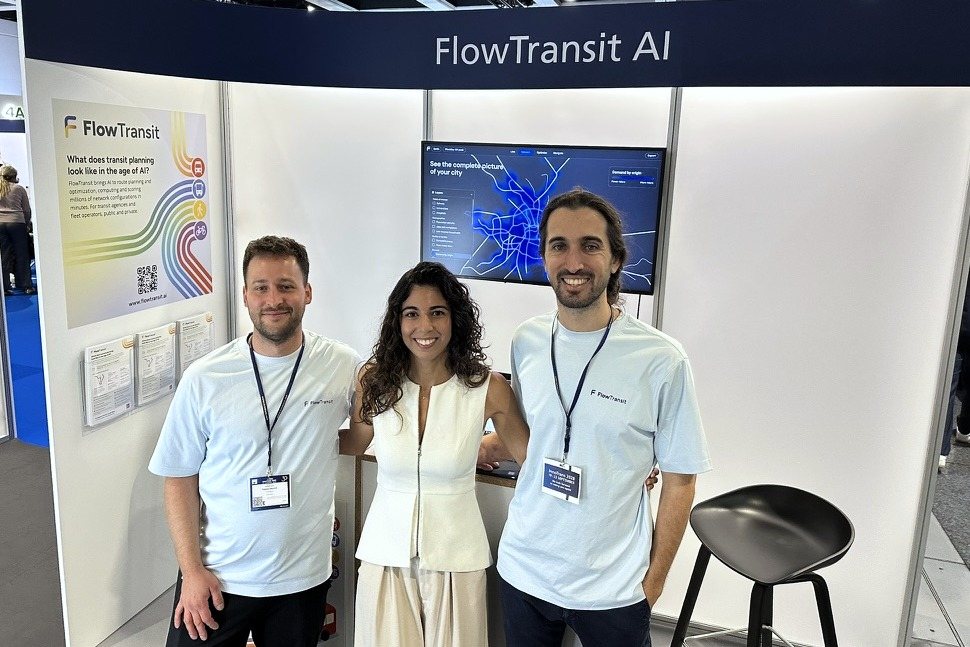 Das FlowTransit-Team vor dem Messestand mit dem Schriftzug FlowTransit AI, auf dem Bildschirm die Planungssoftware